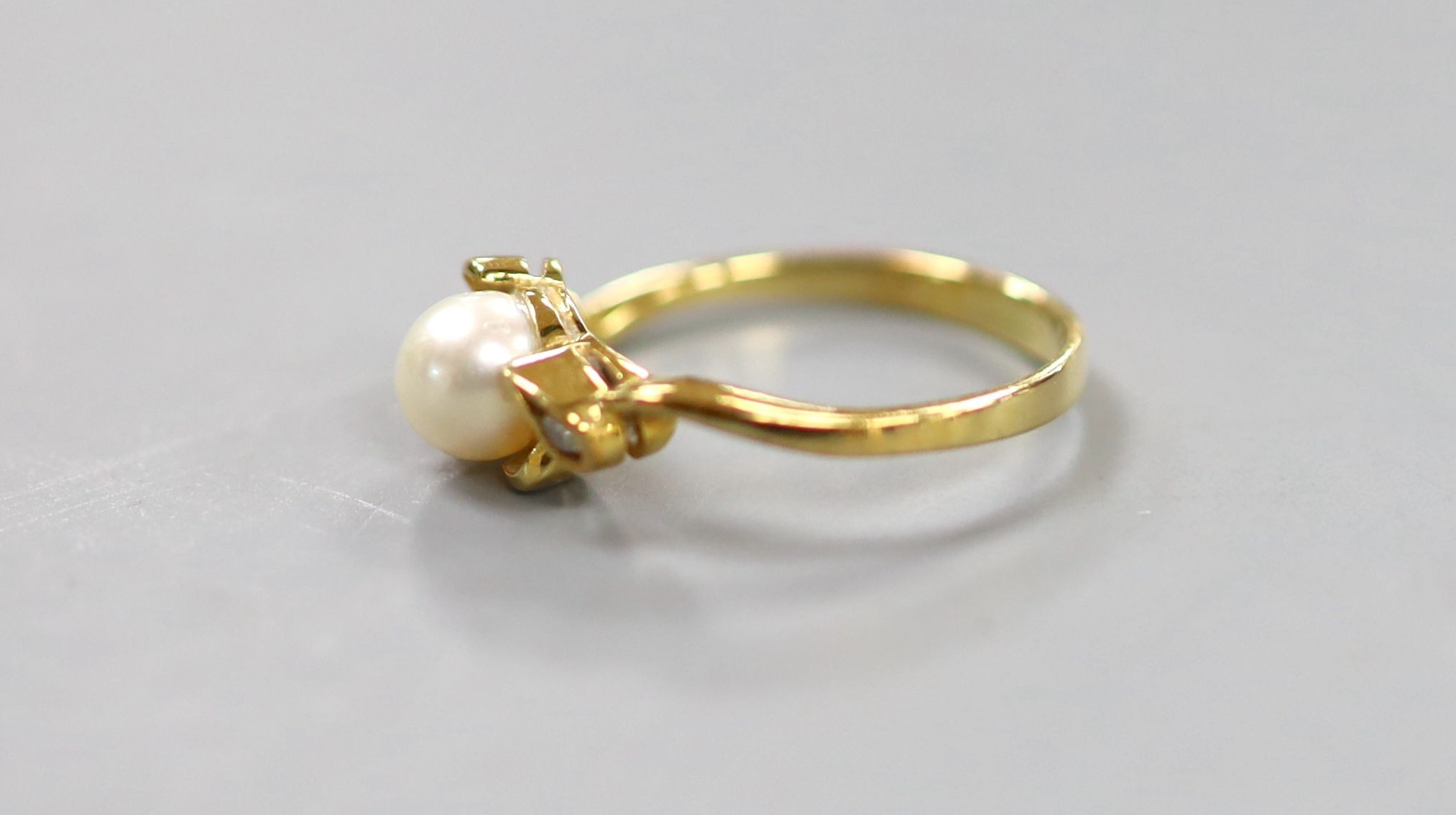 An 18k, single stone cultured pearl and two stone diamond chip set ring, size J, gross 1.9 grams.